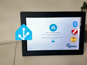 Tablet z czarną ramką wyświetlający polski ekran powitalny aplikacji Home Assistant Companion z nałożonymi logotypami technologii inteligentnego domu takich jak Zigbee, Bluetooth, MQTT i Z-Wave.