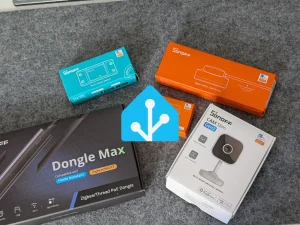 Różne urządzenia smart dom Sonoff, w tym Sonoff Wi-Fi Smart Switch, Zigbee Water Leak Sensor, Dongle Max Zigbee/Thread PoE Dongle oraz Sonoff CAM Slim Gen2 Wi-Fi Smart Security Camera, ułożone wokół niebieskiego logo Home Assistant na szarym tle.