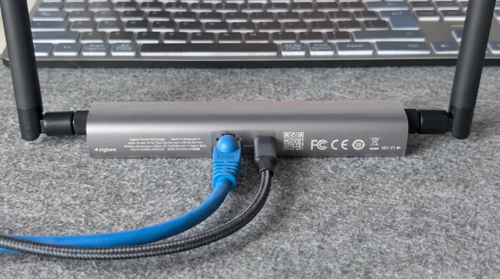 Bramka sieciowa Zigbee i Wi-Fi z podłączonym kablem Ethernet oraz zasilaniem na biurku.